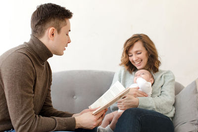 Parents reading book to baby in living room