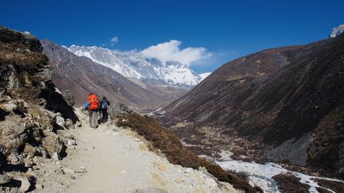 Rear view of man climbing on mountain against sky