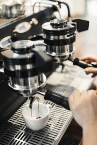 Cropped image of barista using coffee maker at cafe