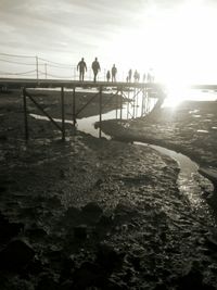 People on beach against sky during sunset