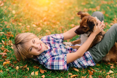 Side view of boy playing with dog on field