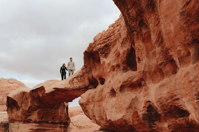 Man on rock formation against sky