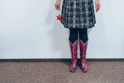 Low section of woman standing against pink wall