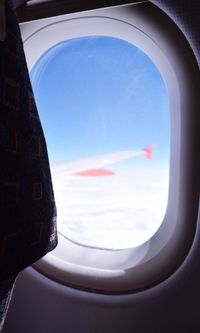 Close-up of airplane wing against sky seen through window
