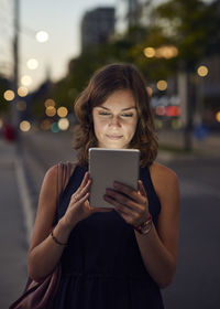 Germany, hamburg, young woman in the street using digital tablet on the move