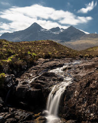 Scenic view of waterfall and mountains against sky