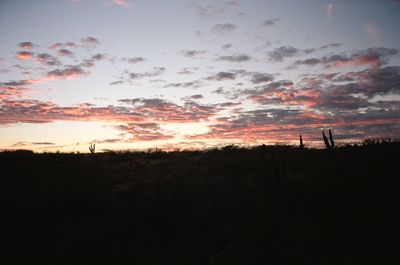 Scenic view of silhouette field against sky at sunset