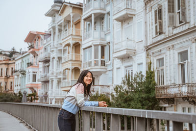 Young woman standing against building