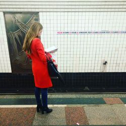 Young woman using phone while standing on tiled floor