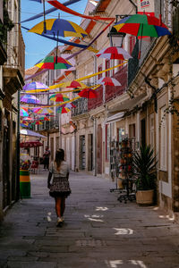 Rear view of woman walking on street amidst buildings