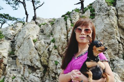 Portrait of woman carrying dog outdoors