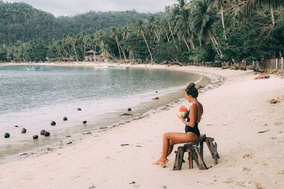 Rear view of woman standing at beach