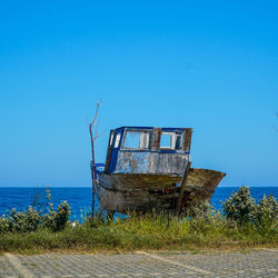 Abandoned boat on beach against clear blue sky