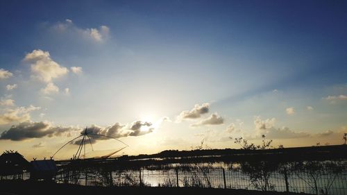 Silhouette bridge over sea against sky during sunset