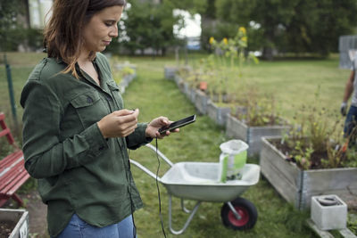 Mid adult woman using mobile phone in community garden