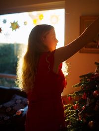 Girl looking away while standing against tree