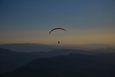 Person paragliding against sky during sunset