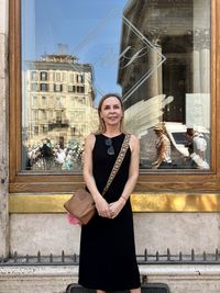 Portrait of young woman standing against building