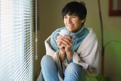 Portrait of young woman drinking coffee at home