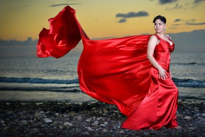 Woman with red umbrella standing on beach