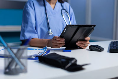 Midsection of nurse looking at digital tablet 