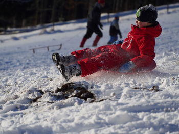 Boy sledding on snow covered field