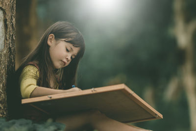 Girl looking away while holding book
