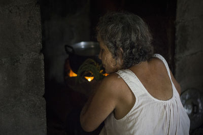 Rear view of woman preparing food in fire pit