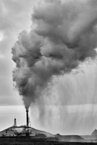 Smoke emitting from chimney against sky