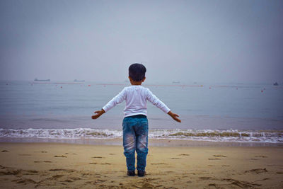 Rear view of child standing on beach