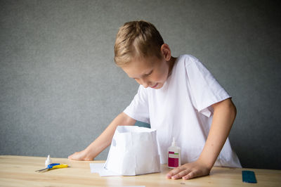 The boy cuts out details from paper. glue the parts together with glue.