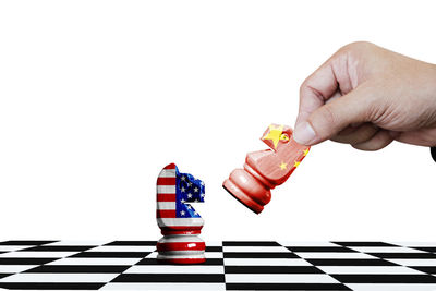 Low angle view of hand holding chess board against white background