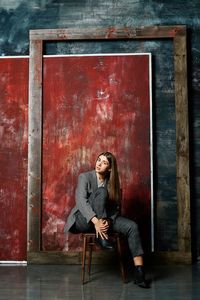 Portrait of woman sitting on chair against wall