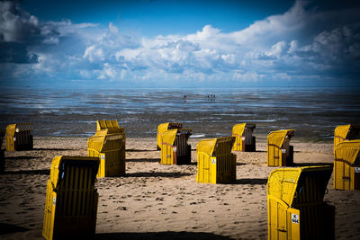 Hooded chairs on beach against sky