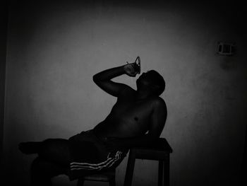 Woman sitting on chair against wall