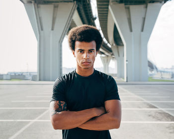 Portrait of young man standing against car