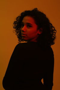 Portrait of woman standing against orange background