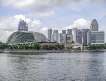 Modern buildings by river against sky in city