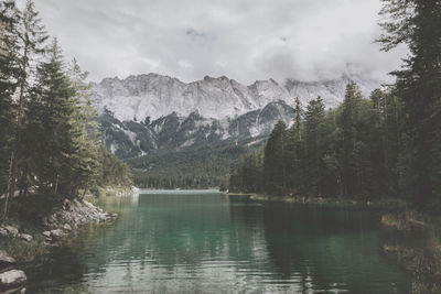 Scenic view of lake and mountains against cloudy sky