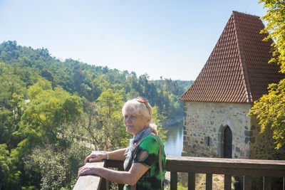 Side view of woman sitting on railing