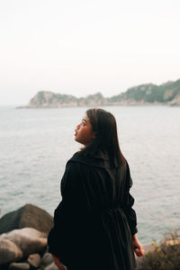 Woman standing by sea against sky