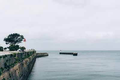 View of lighthouse on pier in sea against sky