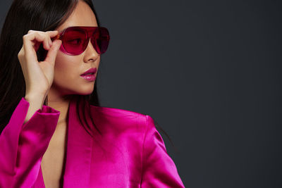 Portrait of young woman wearing sunglasses against black background