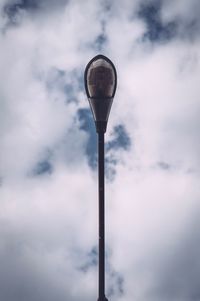 Directly below shot of street light against cloudy sky