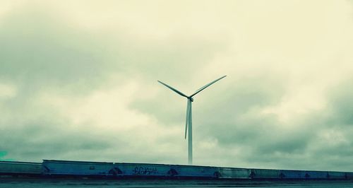 Low angle view of wind turbines against sky