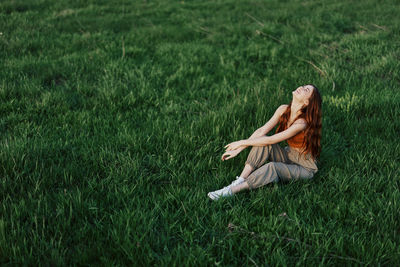 Carefree girl sitting on grass in park