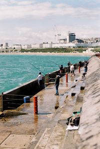 People by sea against buildings in city