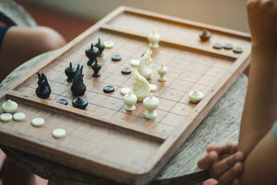 Cropped image of people playing chess on table