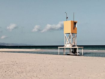 Lighthouse on beach against sky