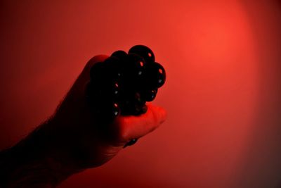 Close-up of hand holding red light against colored background